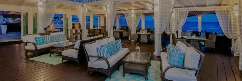 This image features a luxurious seaside dining and lounging area, most likely part of a resort or restaurant
