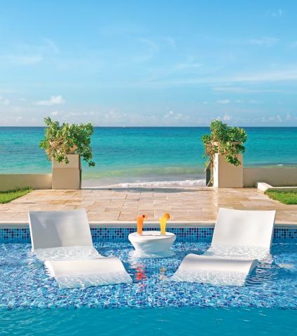 This image features a tranquil and luxurious poolside setting overlooking a beautiful beach
