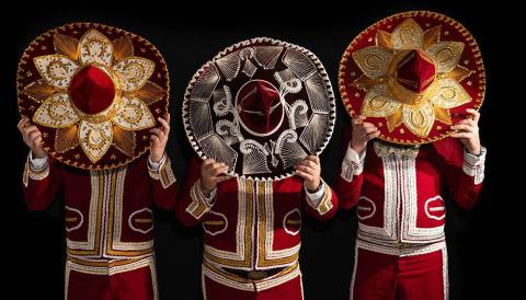 The image features three individuals dressed in extravagant costumes reminiscent of traditional Mexican mariachi or charro outfits but with a unique twist