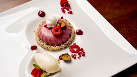 The image features an elegantly plated dessert on a white, uniquely shaped plate