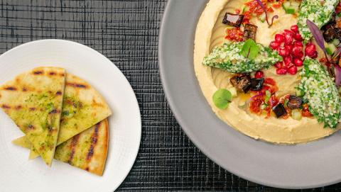 This image features a beautifully presented dish of hummus garnished with various toppings