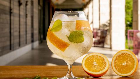 The image features a refreshing drink served in a round goblet glass with ice cubes