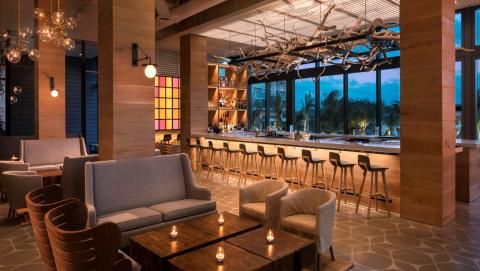 The image shows a stylish and elegantly designed interior of a bar or restaurant at twilight