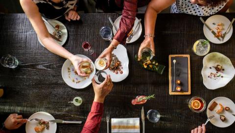Communal dining table with small sharing plates at our Avecita restaurant with four people dining