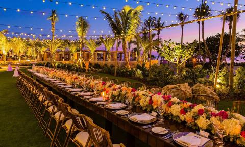 This image features an elegantly set outdoor dining area during what appears to be either twilight or early evening