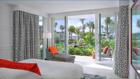 The image shows a modern hotel room with a tropical view