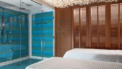 This image shows a modern, luxurious bathroom connected to a bedroom