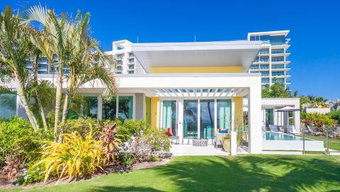The image shows a luxurious modern house with a clear, tropical aesthetic