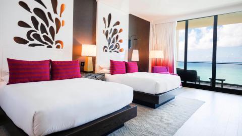 This image shows a modern hotel room with a stunning ocean view