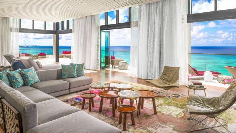 This image shows a modern and stylish beachfront living room with a beautiful panoramic view of the ocean