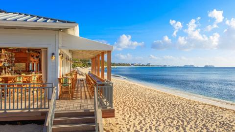 This image depicts a serene beach setting with a beachfront bar or restaurant