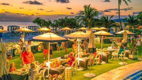 This image shows a lively outdoor evening event at a tropical beachside location