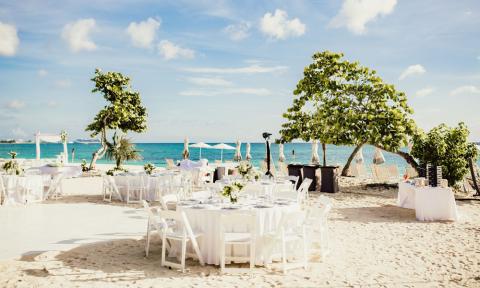 This image shows an elegantly arranged beachside setup for an event, possibly a wedding