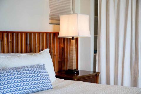 The image shows a cozy bedroom corner featuring a bed with white and patterned blue bedding