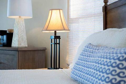 The image shows a cozy bedroom setting featuring two lamps on side tables beside a bed
