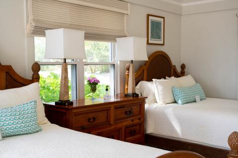 The image shows a well-appointed bedroom featuring two beds with white bedspreads