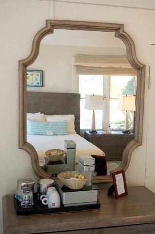 The image shows a decorative set-up featuring a large, uniquely shaped wooden mirror mounted on a white wall