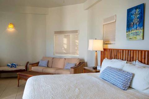 The image shows a neatly arranged interior of a bedroom that also has a small sitting area