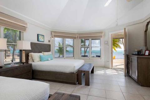 The image shows a bright and airy beachfront bedroom