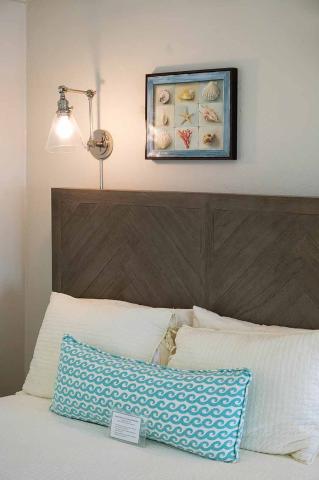 This image depicts a bedroom setup featuring a decorative section of a bed against a wall