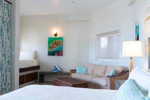This image portrays a neatly arranged hotel or vacation rental room with multiple areas integrated within a single space