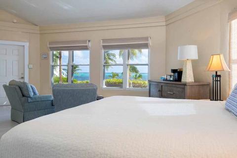This image shows a beautifully arranged bedroom with a clear view of the ocean through windows