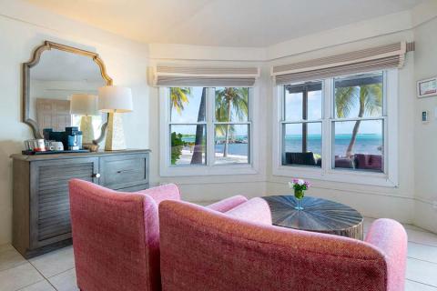 This image shows a cozy, well-furnished room with a beachfront view
