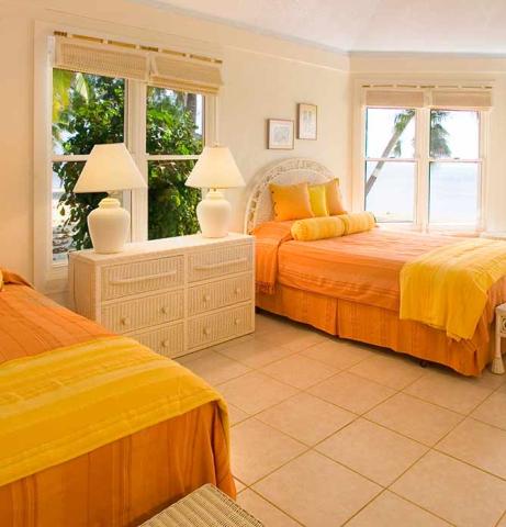The image shows a brightly decorated bedroom with a beachfront view