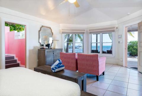 This image shows a bright and well-furnished room that leads directly to a beachfront view