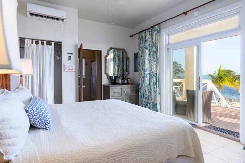 This image shows a brightly lit, contemporary beachfront bedroom