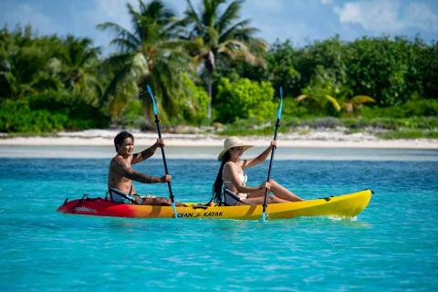 This image shows two people kayaking in a stunning tropical setting
