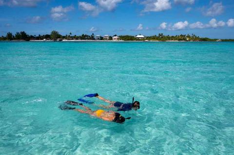 This image shows two people snorkeling in clear, turquoise water
