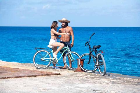 The image shows two people, a man and a woman, enjoying a moment together on a sunny day by the sea