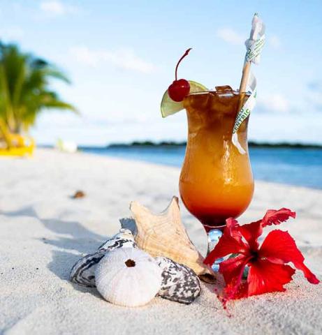 The image features a tropical drink on a sandy beach