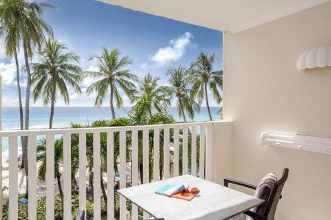 The image shows a scenic view from a balcony looking out to a beautiful beachfront