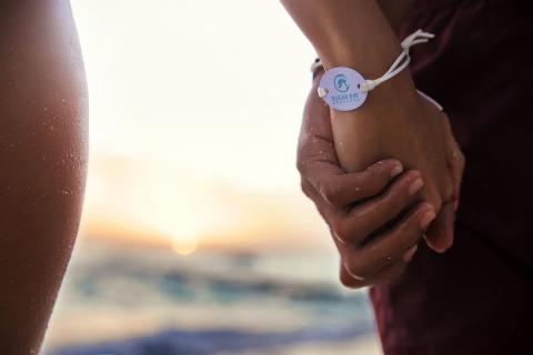 The image shows two people holding hands by the beach