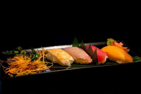 The image shows a beautifully arranged selection of sushi on a black rectangular plate