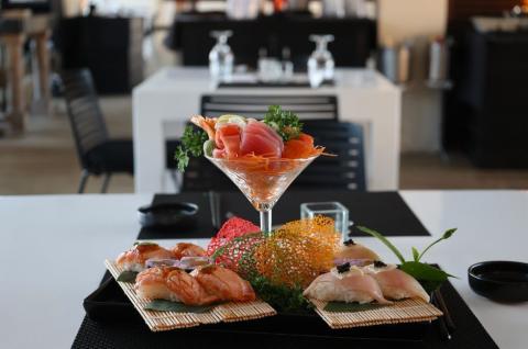 This image shows a visually appealing arrangement of various types of sushi and sashimi presented in a sophisticated setting, likely in a modern sushi restaurant