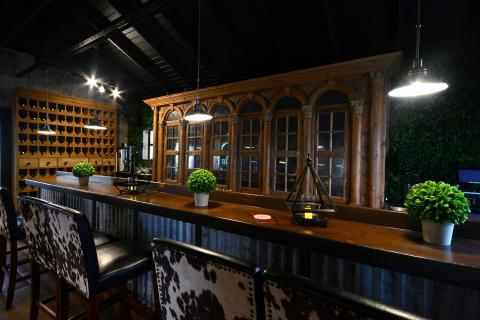 This image shows a stylish and rustic bar setting, featuring a long wooden counter with high stools upholstered in a cowhide pattern