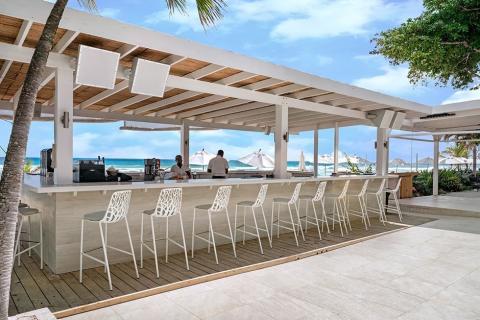 This image shows an elegant beachfront bar with a modern, open-air design