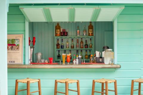 The image shows a charming, tropical-themed outdoor bar
