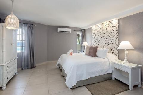 The image displays a well-decorated bedroom, featuring a contemporary and slightly tropical aesthetic