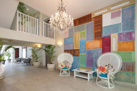 This image shows a stylish and spacious interior, likely a foyer or lounge area, characterized by a modern architecture with tropical design elements