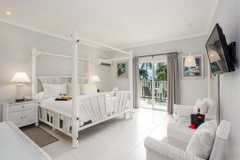 The image shows a bright and airy bedroom with a modern, tropical theme