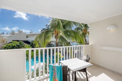The image shows a balcony view overlooking a tropical resort setting