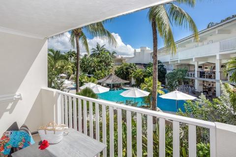 This image shows a view from a balcony overlooking a vibrant tropical resort setting