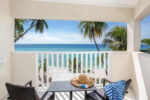 This image features a scenic view from a balcony overlooking a beautiful beachfront