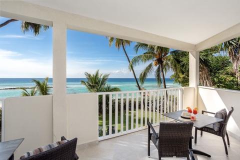 This image features a tranquil balcony view overlooking a beautiful beach