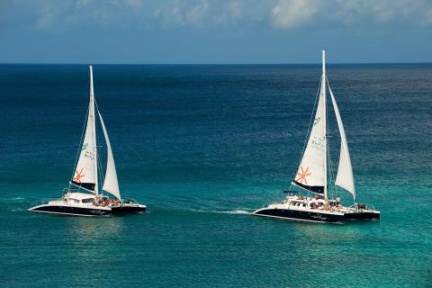 This image shows two catamaran sailboats on a beautiful aqua-blue sea