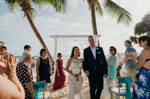 This image captures a joyful beach wedding scene